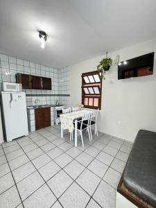 uma cozinha com uma mesa branca e um frigorífico branco em RJ Residencial Nosso Sonho com Piscina a 120m mar em Palhoça