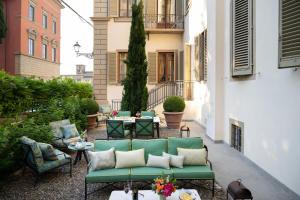 un patio con un sofá verde, mesas y sillas en Serristori Palace Residence, en Florencia