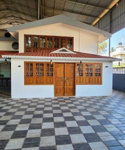 une maison avec des portes en bois et un sol en damier dans l'établissement Bharatham Heritage Inn, à Kannur