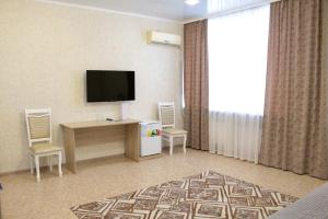 Habitación de hotel con TV, escritorio y sillas. en гостиница Павлодар, en Pavlodar