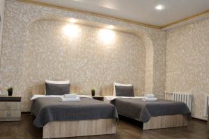 een slaapkamer met 2 bedden en een muur bij гостиница Павлодар in Pavlodar