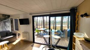 sala de estar con balcón con mesa y sillas en LE COTTAGE VUE LAC-2 vélos-Village Vacances Nature de 70ha! avec piscines et animations en Léon