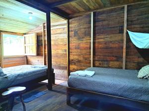 a room with two beds in a wooden cabin at Rainforest Hut in Archidona
