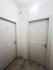 - deux portes blanches dans une chambre revêtue de carrelage dans l'établissement Palazzo Elios, à Parme