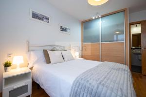 ein Schlafzimmer mit einem weißen Bett und einer Glasschiebetür in der Unterkunft Dúplex Nalón in San Juan de la Arena