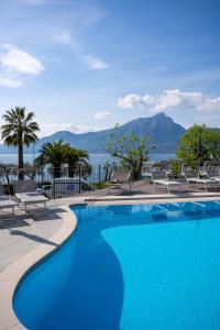 una piscina con sillas y montañas en el fondo en Hotel Galvani, en Torri del Benaco