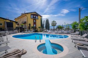 una piscina en un hotel con sillas y un edificio en Hotel Galvani, en Torri del Benaco