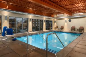 Hampton Inn and Suites Clayton/St. Louis-Galleria Area في كلايتون: حمام سباحة داخلي كبير في الفندق مع الكراسي والطاولات