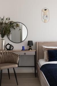 a bedroom with a mirror and a couch and a table at Scala Apartamenty by Moderna Profit- Łąkowa 60E z parkingiem in Gdańsk
