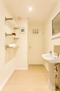a white bathroom with a sink and a mirror at Fabulous Beach Pad Just 20 Paces From The Sea in Mawgan Porth