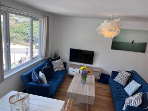 a living room with a blue couch and a table at Fabulous Beach Pad Just 20 Paces From The Sea in Mawgan Porth