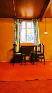 a table and two chairs in a room with a window at Woodside Bungalow1 in Ooty