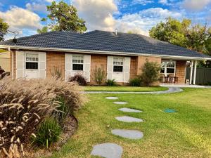 a house with a pathway in front of a yard at Parkview Cottage in Henley Beach South