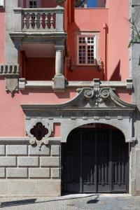 a pink building with a gate and a balcony at Porto Deluxe Palace in Porto