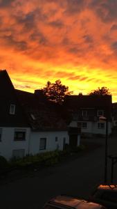 um pôr-do-sol sobre uma casa branca com um céu vermelho em Pension Sonnenheim em Winterberg