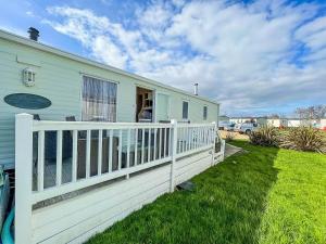 una casa con una cerca blanca al lado de un patio en Brilliant Caravan With Decking And Wifi At Dovercourt Park In Essex Ref 44010a, en Great Oakley