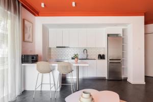 cocina con armarios blancos y techo naranja en OneZeroTwo by Zoia Living, en Atenas