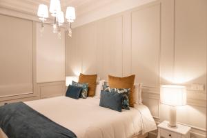 a bedroom with a large white bed with blue pillows at Porto Deluxe Palace in Porto