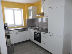 a kitchen with white cabinets and a sink at Ferienwohnungen Flora in Bad Windsheim