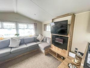 a living room with a couch and a flat screen tv at Lovely Caravan With Decking Wifi At Dovercourt Park, Essex Ref 44003bv in Great Oakley