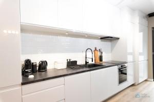 una cocina con armarios blancos y fregadero en Garden Studio by 3City Rentals en Gdynia
