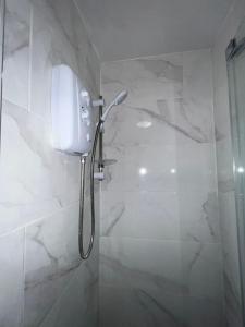 a shower in a bathroom with white marble walls at OYO Greenway Stays in Uxbridge