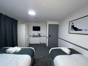 Habitación de hotel con 2 camas y TV en OYO Greenway Stays, en Uxbridge