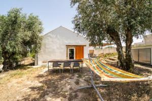 a table and a hammock in front of a house at Casa da Figueira - Pool and Lounge in Praia do Ribatejo