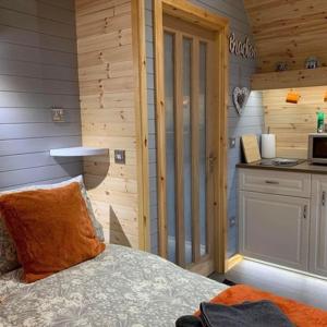 a bedroom with a bed and a kitchen in a cabin at Daviot Luxury Pods in Inverness