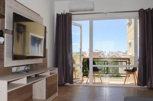 Una sala de estar con televisión y un balcón. en Linea Recta Sur- Huemul, departamento amplio, de 3 dormitorios a pasos del mar, en Puerto Madryn