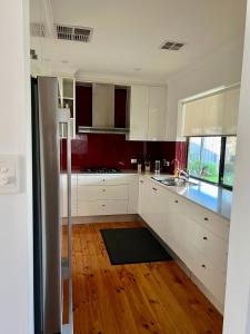 een keuken met witte kasten en een houten vloer bij Parkview Cottage in Henley Beach South