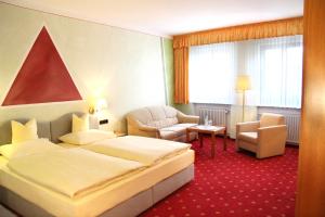 a hotel room with a bed and a chair at Hotel-Garni Goldener Schwan in Bad Windsheim