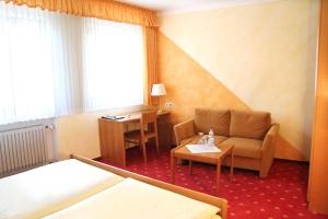 a hotel room with a bed and a chair and a desk at Hotel-Garni Goldener Schwan in Bad Windsheim