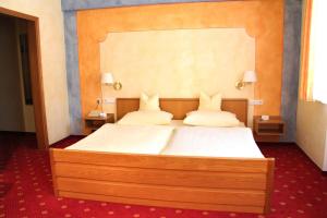 a bedroom with a large bed with white sheets and pillows at Hotel-Garni Goldener Schwan in Bad Windsheim