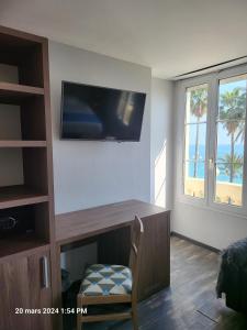 a room with a desk with a television on the wall at Hotel Flots d'Azur in Nice