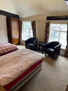 a hotel room with two beds and chairs and windows at The bucks head hotel in Church Stretton