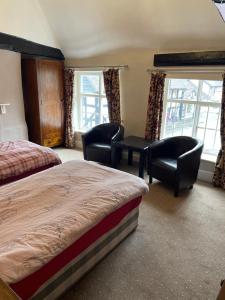 a hotel room with two beds and chairs and windows at The bucks head hotel in Church Stretton