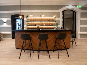 a bar with four stools in front of a counter at DORMERO Hotel Worms in Worms