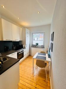 a kitchen with white cabinets and a table with chairs at Schönes 2-Zimmer-Apartment in Bremen, Findorff in Bremen