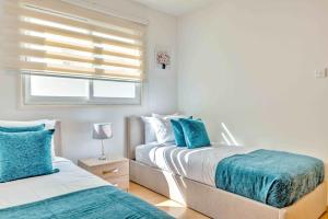 - 2 lits dans une chambre blanche avec des oreillers bleus dans l'établissement Phaedrus Living: Modern City Flat Elpida, à Strovolos