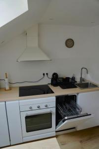 a white kitchen with a stove and a sink at Studio rénové dans le centre in Cauterets