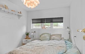 een witte slaapkamer met een bed en een raam bij Nice Home In Brkop With House Sea View in Børkop