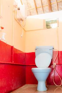 a bathroom with a white toilet in a red wall at Hippie Land Nature Stay in Hampi