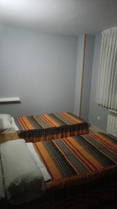 a bedroom with two beds and a rug on the floor at HOSTAL CEPA DE ORO in Aranda de Duero
