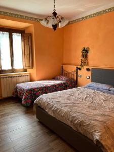 two beds in a bedroom with orange walls at B&B da Paola in Bardalone