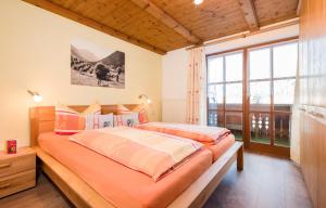 two beds in a bedroom with a large window at Landhaus Pichler in Tannheim
