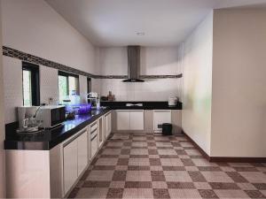 uma cozinha com armários brancos e um piso xadrez em Manee Poolvilla em Khanom