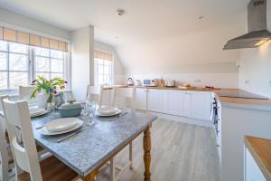 a kitchen with a dining table and a kitchen with white cabinets at 4 Truman Lodge in Thorpeness