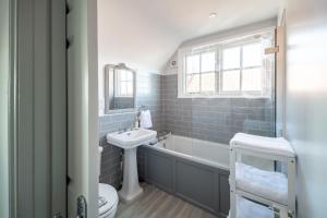 a bathroom with a sink and a tub and a toilet at 4 Truman Lodge in Thorpeness