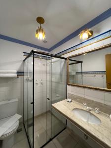 uma casa de banho com um lavatório e uma cabina de duche em vidro. em Pousada Sinhá Olímpia em Ouro Preto